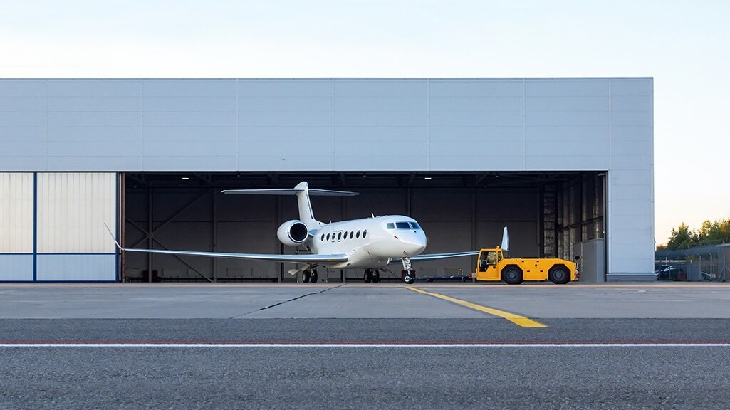 business jet is being towed out of the hangar