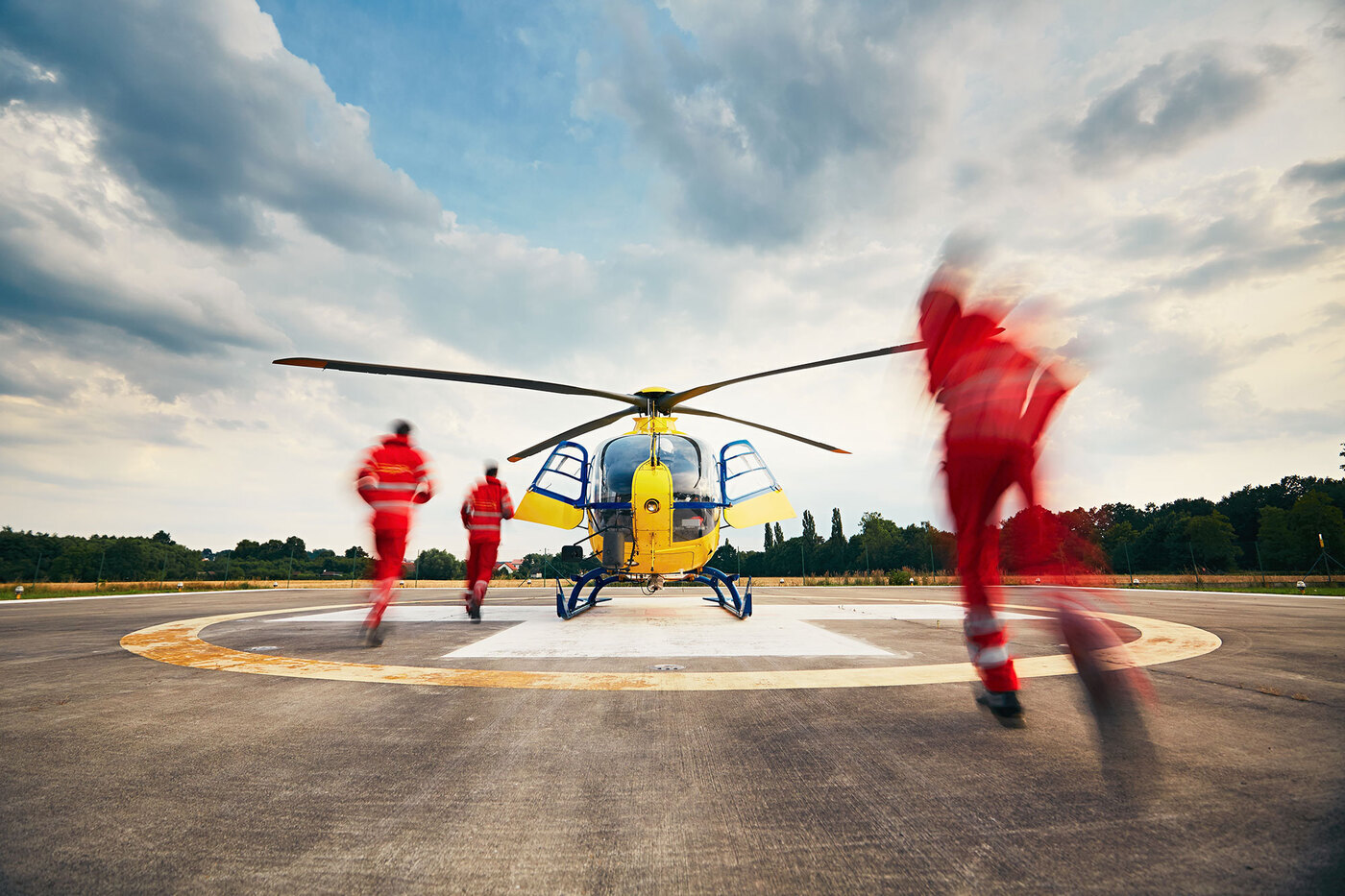 Air rescue service team running to the helicopter on the heliport