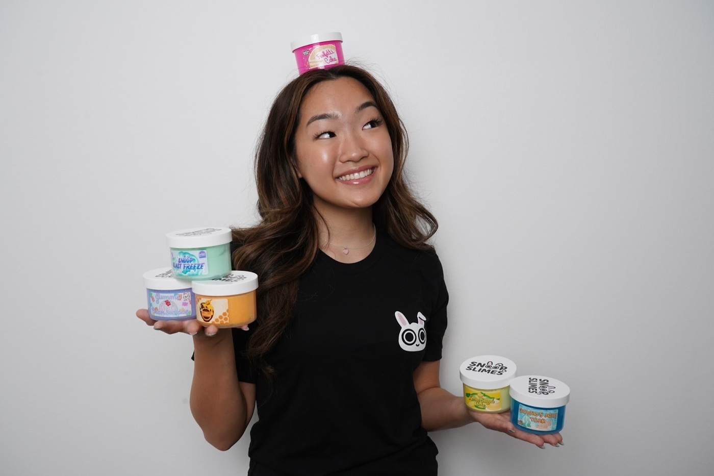 Headshot of Jungmin Kang with several containers of SnoopSlimes products