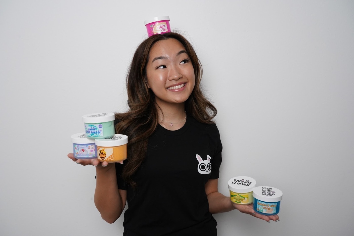 Headshot of Jungmin Kang, founder and CEO of SnoopSlimes holding several containers of her product