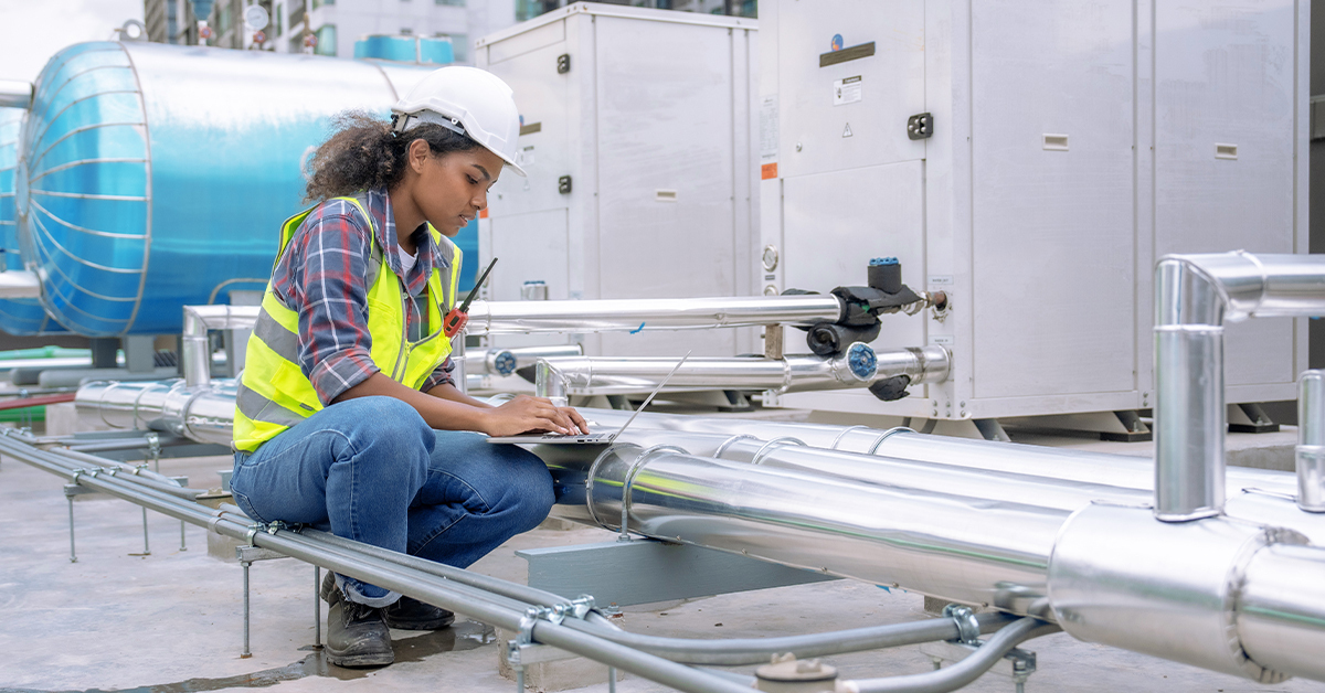 Female engineer inspects factory air conditioner.