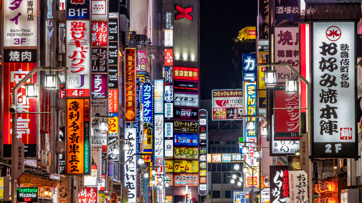 A vibrant and colorful street scene in Tokyo, Japan, featuring numerous illuminated signs and billboards, symbolizing the integration of advanced technology and urban life as envisioned by Society 5.0.