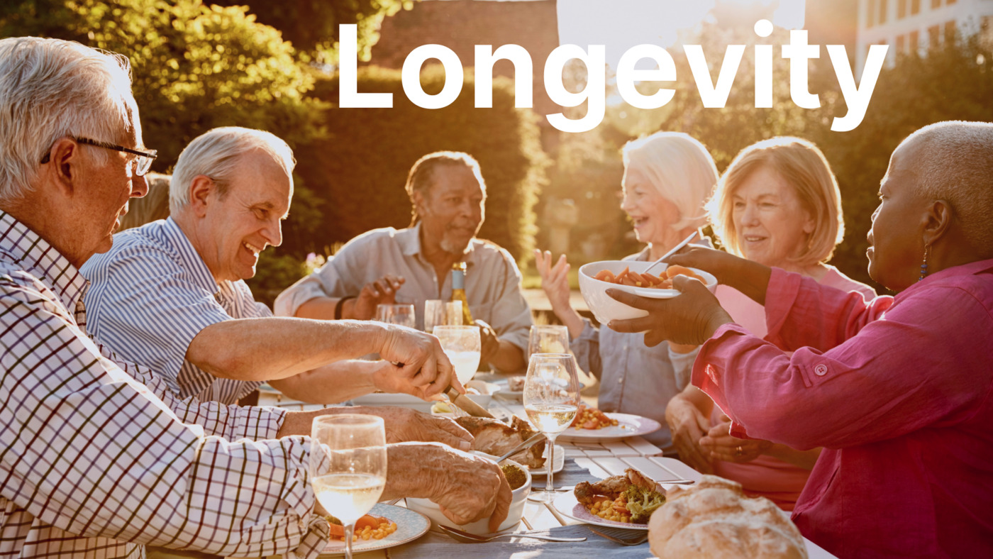 Elderly individuals enjoying a meal outdoors, symbolising longevity and the benefits of healthy lifestyles, social connections, and the Mediterranean diet.