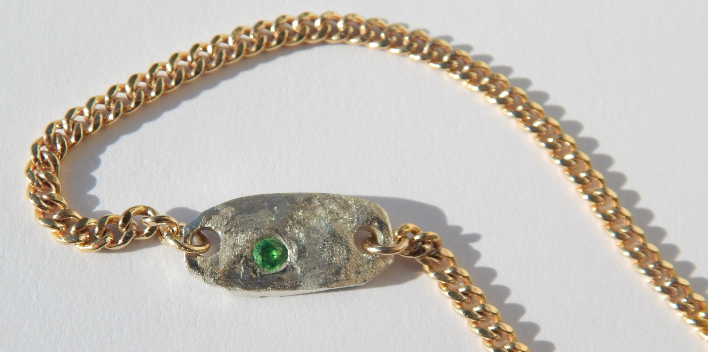 Gold-filled Cuban chain necklace with a hand-carved sterling silver charm featuring a green gemstone, photographed on a clean white background