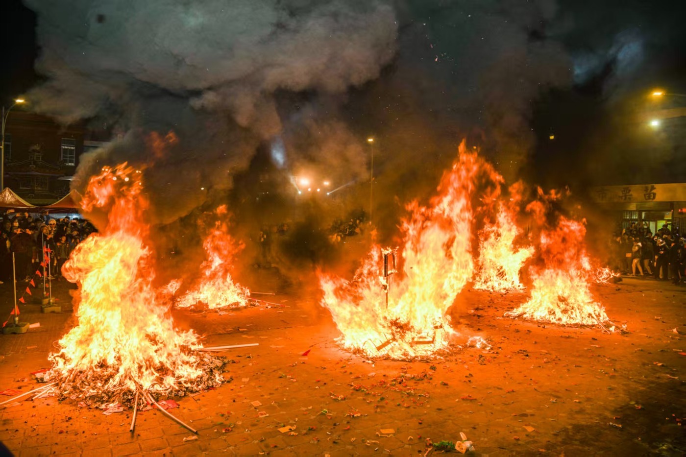 Seven Stages of Dragon Bombing Final Chapter [Ascension of the Dragon]: After receiving its final baptism of firecrackers, the auspicious dragon is ignited by the dragon hosts with the sacred flame, which is first lit by the chief officiant using the ceremonial document. As smoke rises into the sky, the Dragon God ascends back to the heavenly realm.