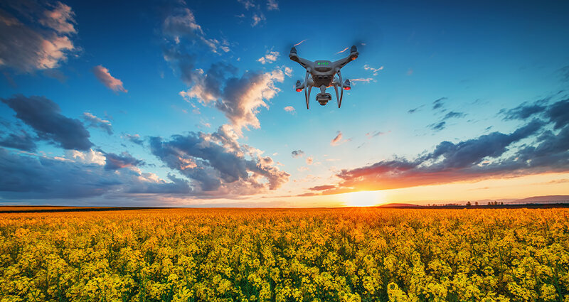 Flying drone over field in spring with dramatic sunset clouds
