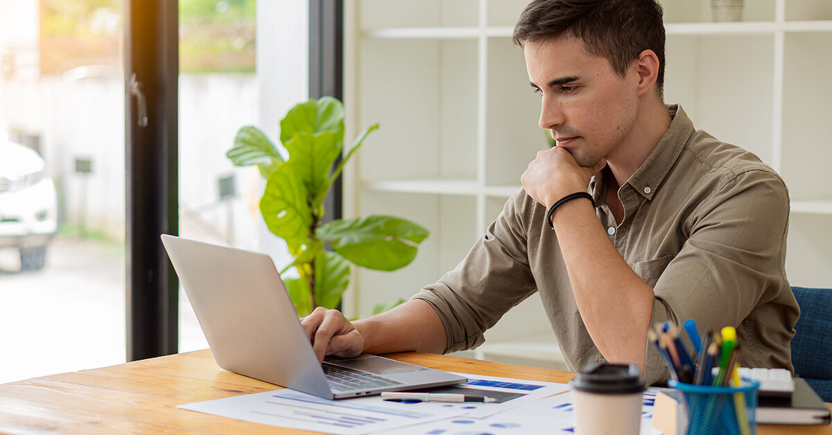 Man uses laptop and sits at a table.