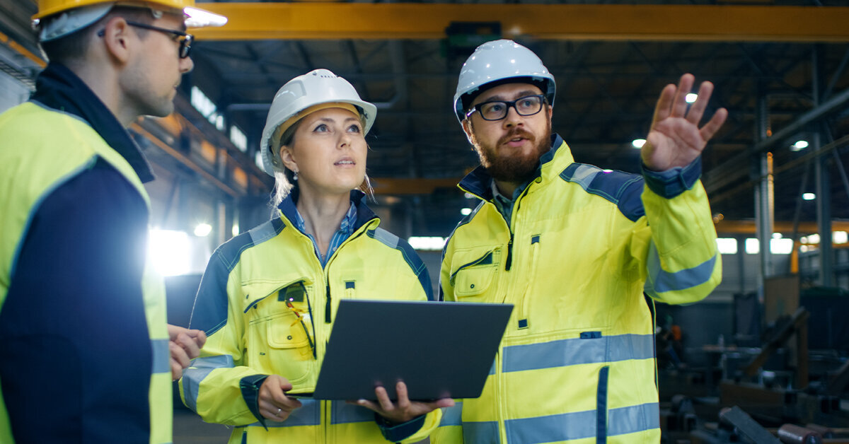 Two OSHA inspectors on a job site look off into the distance.
