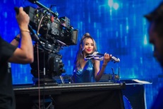 Esther Anaya holding a violin on the set of the Cadillac and iHeartMedia commercial 